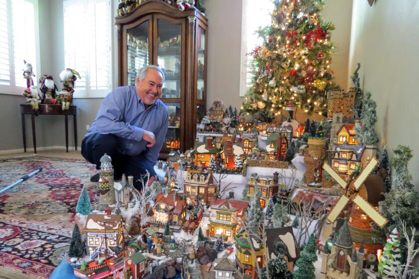 Scripps Ranch resident Mike Kompanik, 64, admires his enormous illuminated Victorian village holiday display in the den of his home on Dec. 13. Kompanik, a retired Navy captain, has been building his collection over the past 34 years.