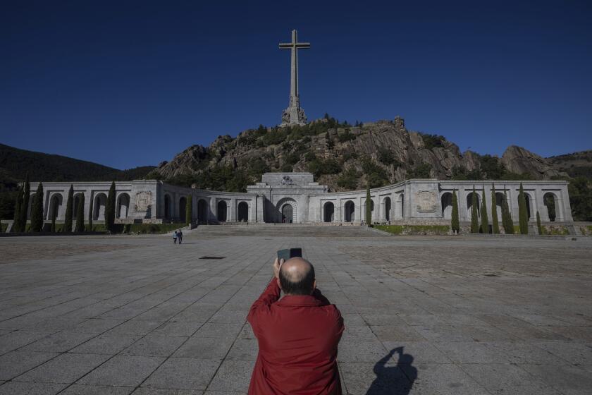 A visitor takes a snapshot at the Valley of the Fallen mausoleum near El Escorial, outskirts of Madrid, Spain, Tuesday, Sept. 24, 2019. The Spanish Supreme Court has ruled that the caretaker Socialist government can exhume the remains of former dictator Gen. Francisco Franco. Leftist parties and families of many Spanish Civil War victims have long wanted Franco to be removed from the mausoleum, which is a major tourist attraction. Others argue this would open old wounds. (AP Photo/Bernat Armangue)
