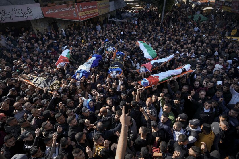Mourners carry the bodies of eight Palestinians, some draped in the flag of the Islamic Jihad militant group, during a joint funeral in the West Bank city of Jenin, Thursday, Jan. 26, 2023. Israeli forces killed at least nine Palestinians, including a 60-year-old woman, and wounded several others during a raid in the flashpoint area of the occupied West Bank, Palestinian health officials said, in one of the deadliest days of fighting in years. The Israeli military said it was conducting an operation to arrest militants when a gun battle erupted. (AP Photo/Majdi Mohammed)