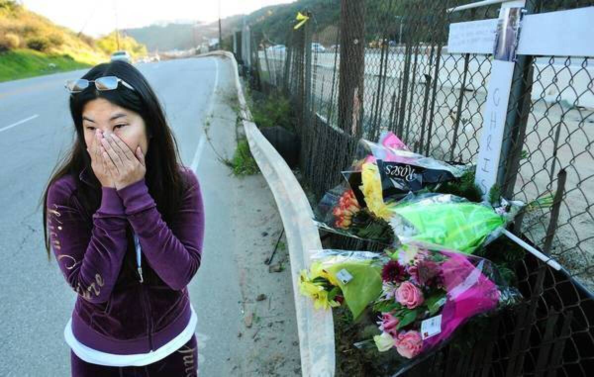 Frances Merto, the girlfriend of photographer Chris Guerra, stands at a memorial along Sepulveda Boulevard near Getty Center Drive. Guerra was struck by a vehicle and killed Tuesday night after taking pictures of Justin Bieber's car.