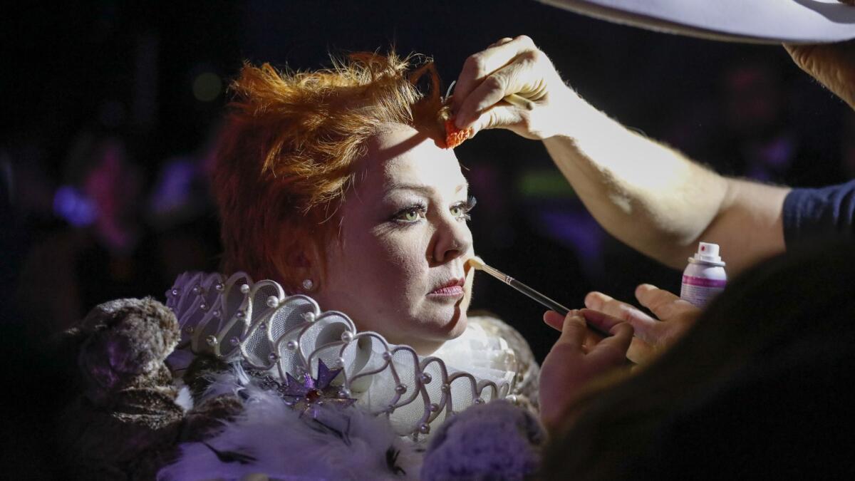 Melissa McCarthy gets prepped for her entrance in a royal gown adorned with plush rabbits and hand puppets.