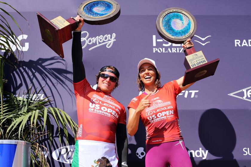 Alan Cleland of Mexico, wins the Men's final, left, and Sally Fitzgibbons of Australia wins the women's final, they hold up their the 2024 U.S. Open of Surfing trophy during the U.S. Open of Surfing trophy celebrations at the Huntington Beach Pier in Huntington Beach on Sunday, August 11, 2024. (Photo by James Carbone)