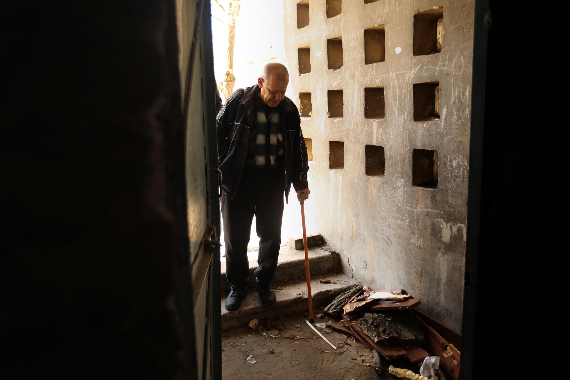 A man with a cane walks down a step.