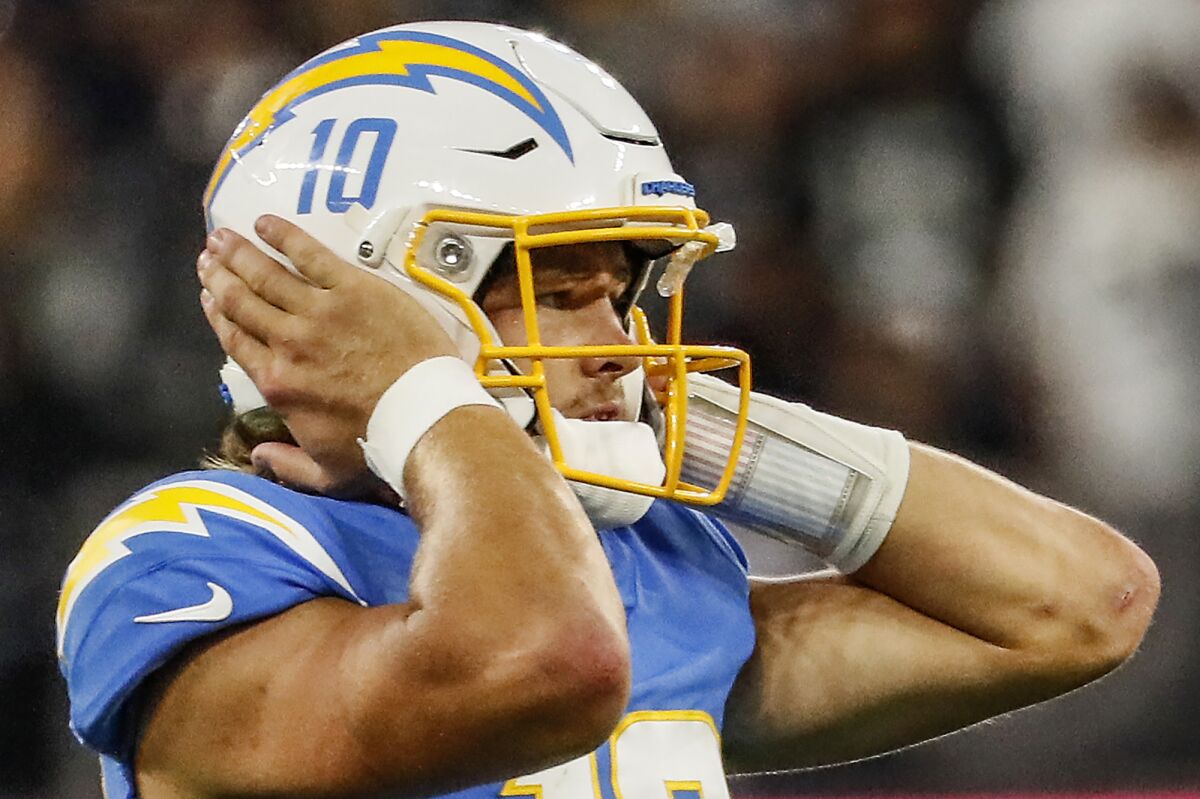Chargers quarterback Justin Herbert (10) blocks out ambient noise while trying to hear the play call.