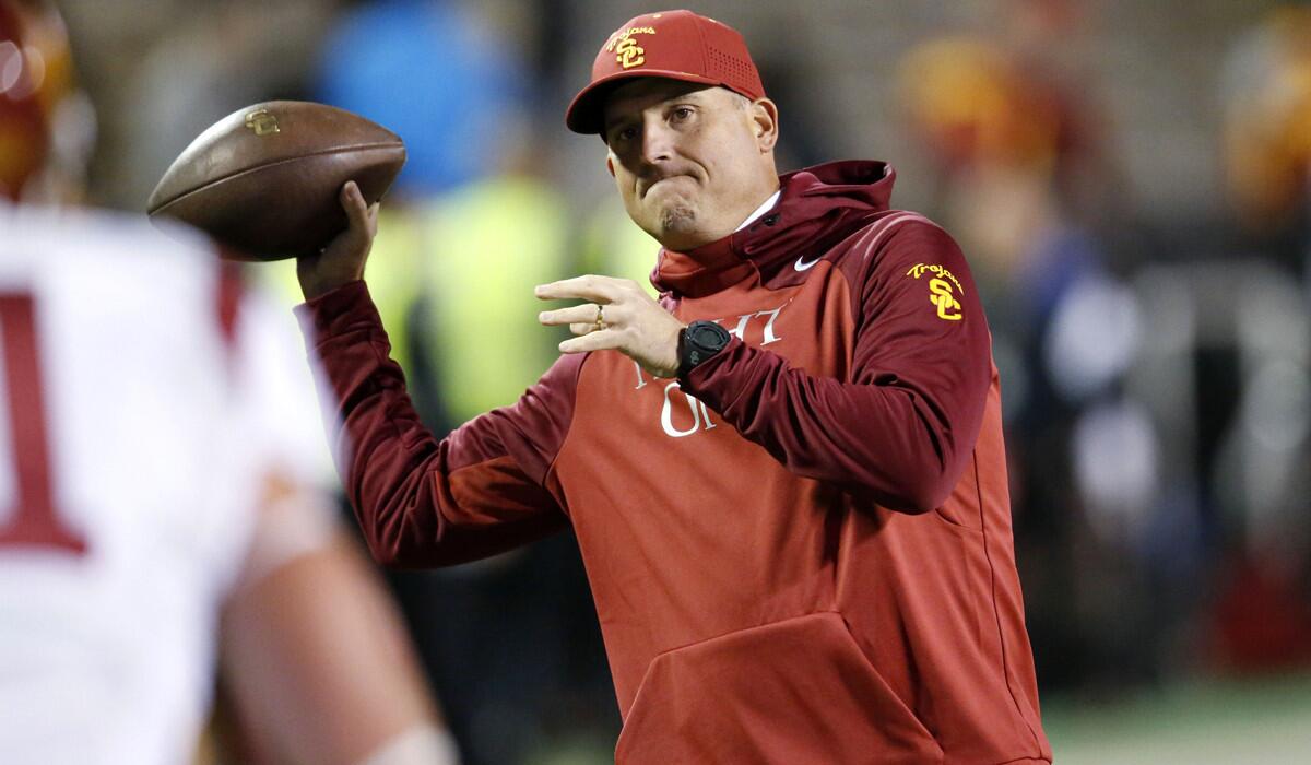 USC interim head coach Clay Helton gets ready to pass the ball on the sideline before a game against Colorado last Friday.