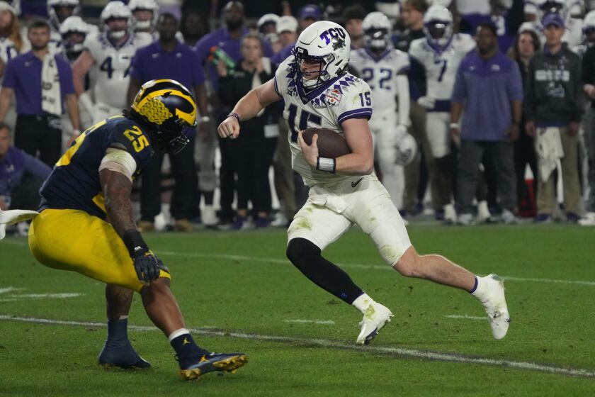 FILE - TCU quarterback Max Duggan (15) runs as Michigan linebacker Junior Colson (25) defends during the second half of the Fiesta Bowl NCAA college football semifinal playoff game, Dec. 31, 2022, in Glendale, Ariz. TCU had quite a conference-hopping journey on way to the national championship game after the small private school deep in the heart of Texas was left out of the original Big 12 lineup. (AP Photo/Rick Scuteri, File)