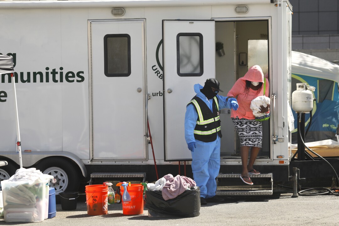 A man in a reflective vest helps a woman step down from a trailer