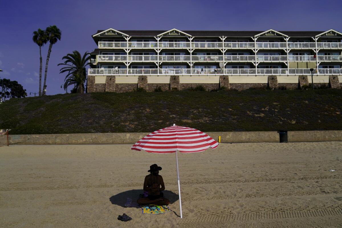 A beachgoer sits in the shade under an umbrella in Redondo Beach, Calif., Wednesday, Sept. 7, 2022. Western states are struggling through one of the hottest and longest September heat waves on record. Temperatures began soaring last week and the National Weather Service warned that dangerous heat could continue through Friday, despite some slight moderation. (AP Photo/Jae C. Hong)