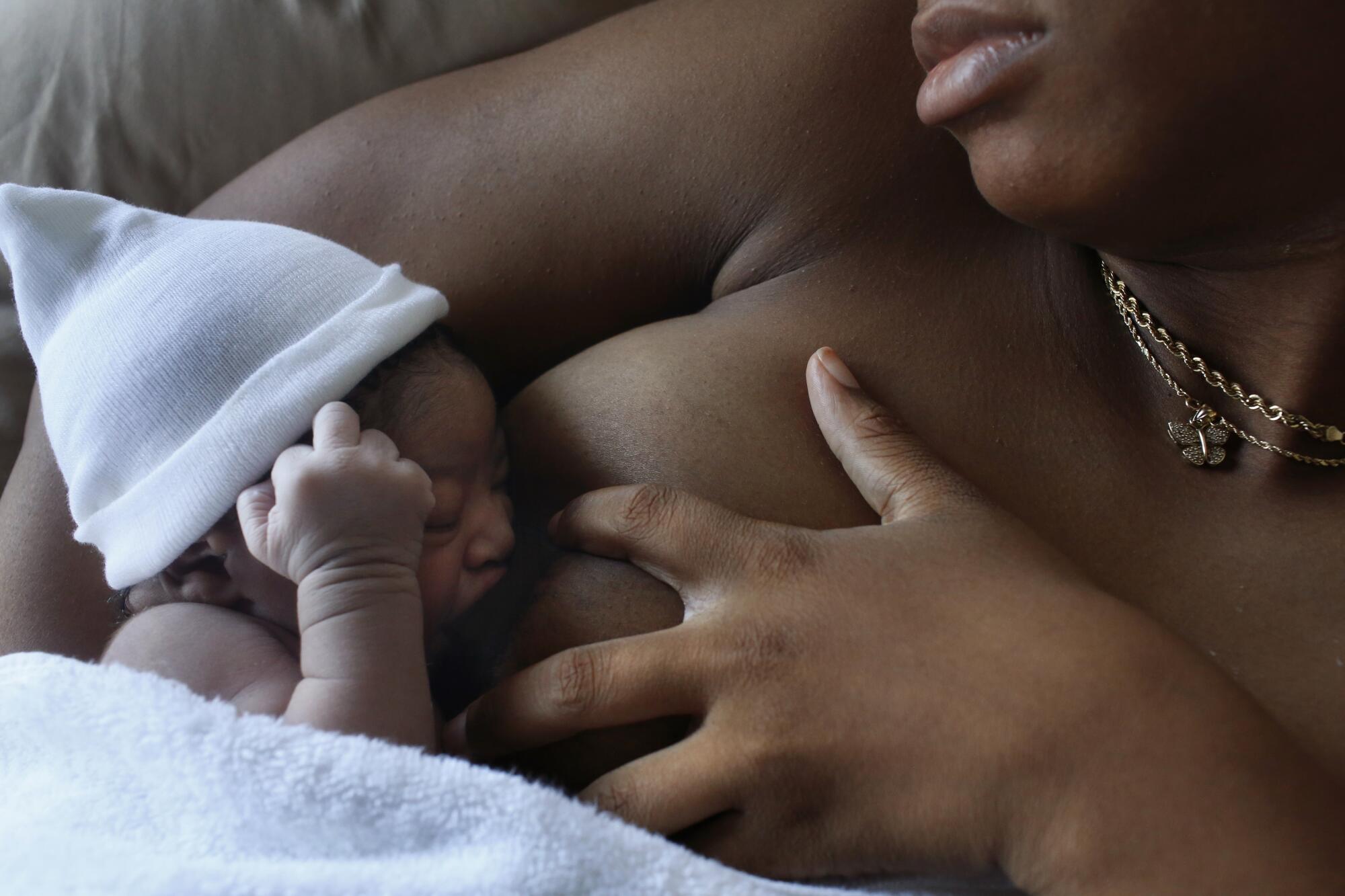 A woman breast-feeds her newborn