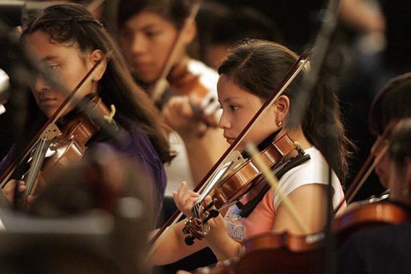 Arlette Romero, 11, center, plays her violin during a rehearsal for the YOLA Expo Center Youth Orchestra's debut at the Hollywood Bowl as part of the "?Bienvenido Gustavo!" concert.