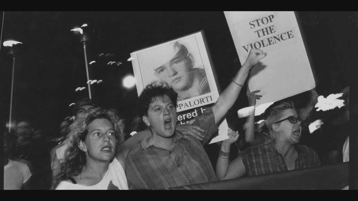 A black-and-white image of protestors at a rally against killings of queer men in New York.