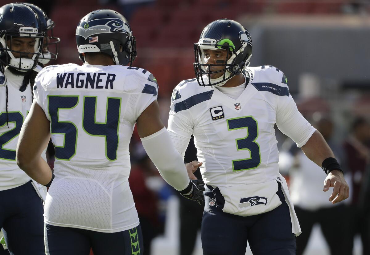 Linebacker Bobby Wagner (54) greets quarterback Russell Wilson (3) when they were Seattle Seahawks teammates.