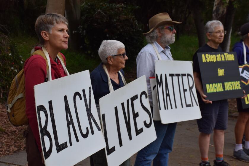 a group stands outside in a park holding Black Lives Matter signs