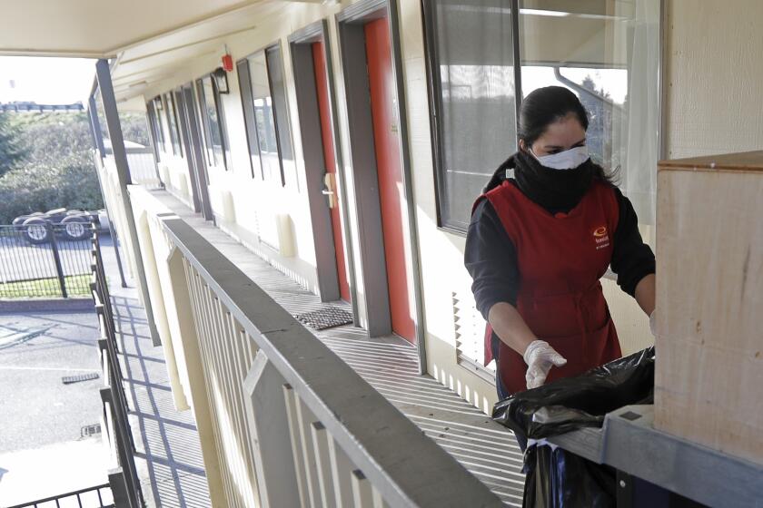 A housekeeping worker wears a mask as she cleans a room, Wednesday, March 4, 2020, at an Econo Lodge motel in Kent, Wash. King County Executive Dow Constantine said Wednesday that the county had purchased the 85-bed motel south of Seattle to house patients for recovery and isolation due to the COVID-19 coronavirus. (AP Photo/Ted S. Warren)