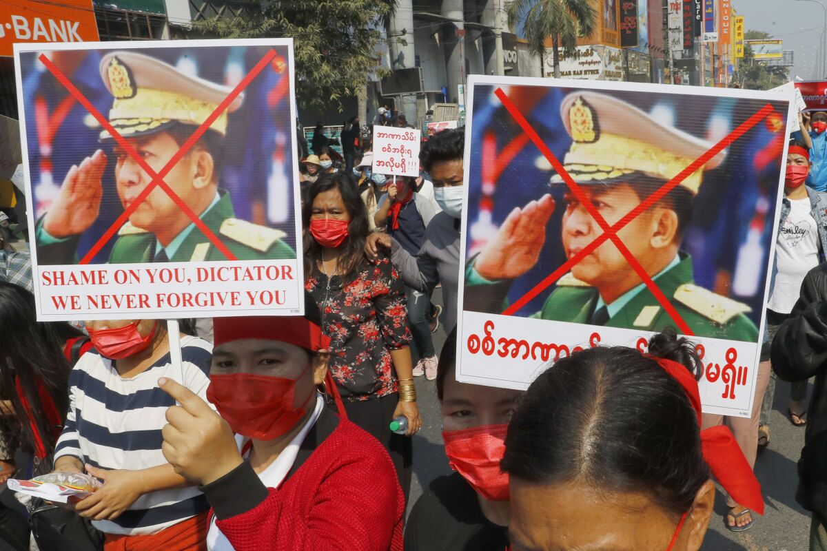 Protesters hold placards with an X mark on the image of Myanmar Senior Gen. Min Aung Hlaing.