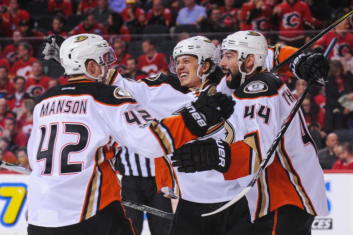 Ducks' Josh Manson (42), Rickard Rakell and Nate Thompson (44) celebrate the winning goal of their teammate Corey Perry against the Calgary Flames on Monday night.
