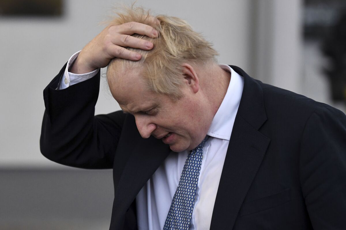 Boris Johnson puts a hand on his head.