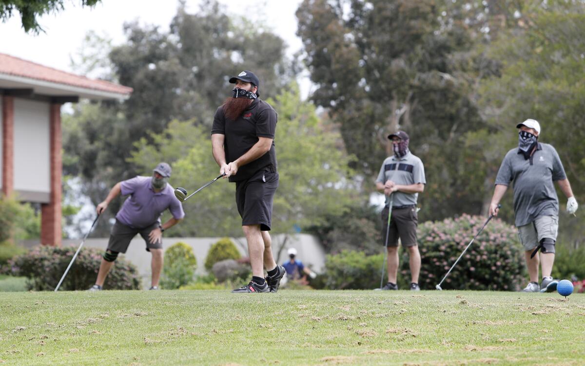 Golfer Eddie Rodriguez, 30, tees off as he begins a round of golf with, from left to right, Nick Pederson, 29, brother Justin Rodriguez, 29, and Todd Carbello, 58, at Costa Mesa Country Club on Wednesday.