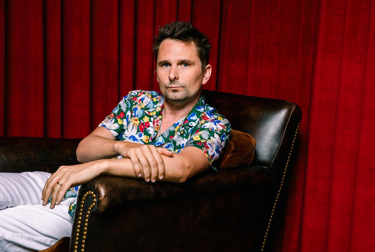 A man in a flowered shirt sits in a leather armchair