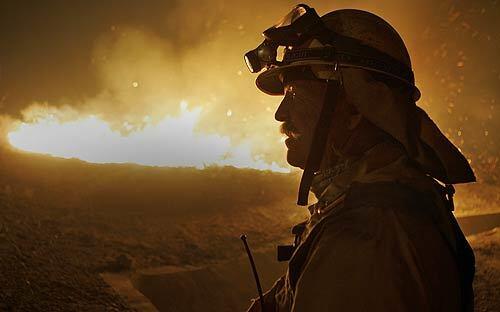 Orange County Fire Authority firefighter Bernie Brawner walks the fire line near Portola Parkway and Sand Canyon Avenue in Irvine, where a fast-moving blaze swept out of the hills and moved along the 241 toll road near the 133 Freeway.