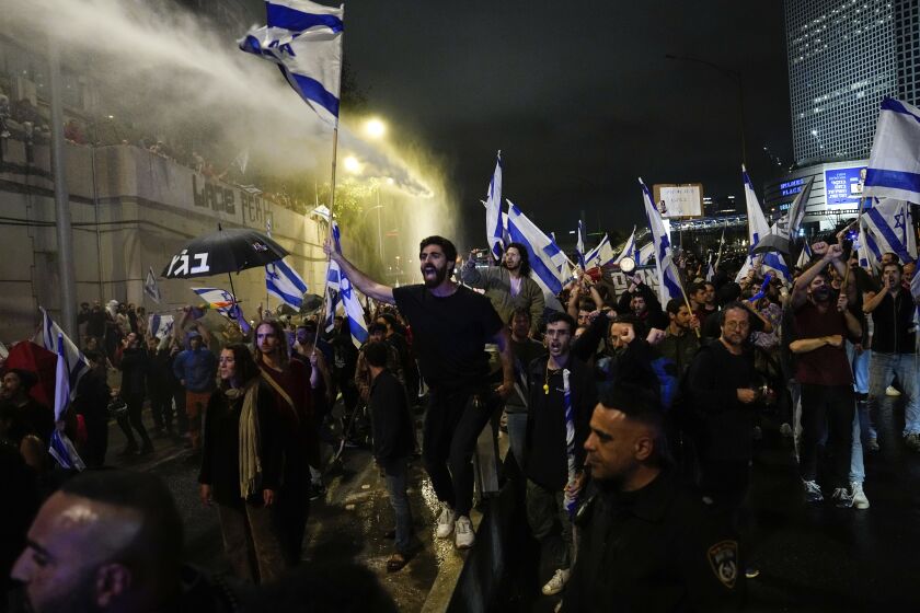 La policía israelí usa un cañón hidrante para dispersar a los manifestantes que bloquean una autopista como protesta contra el plan del primer ministro Benjamin Netanyahu de reformar el sistema judicial, en Tel Aviv, Israel, 25 de marzo de 2023. (AP Foto/Ariel Schalit)