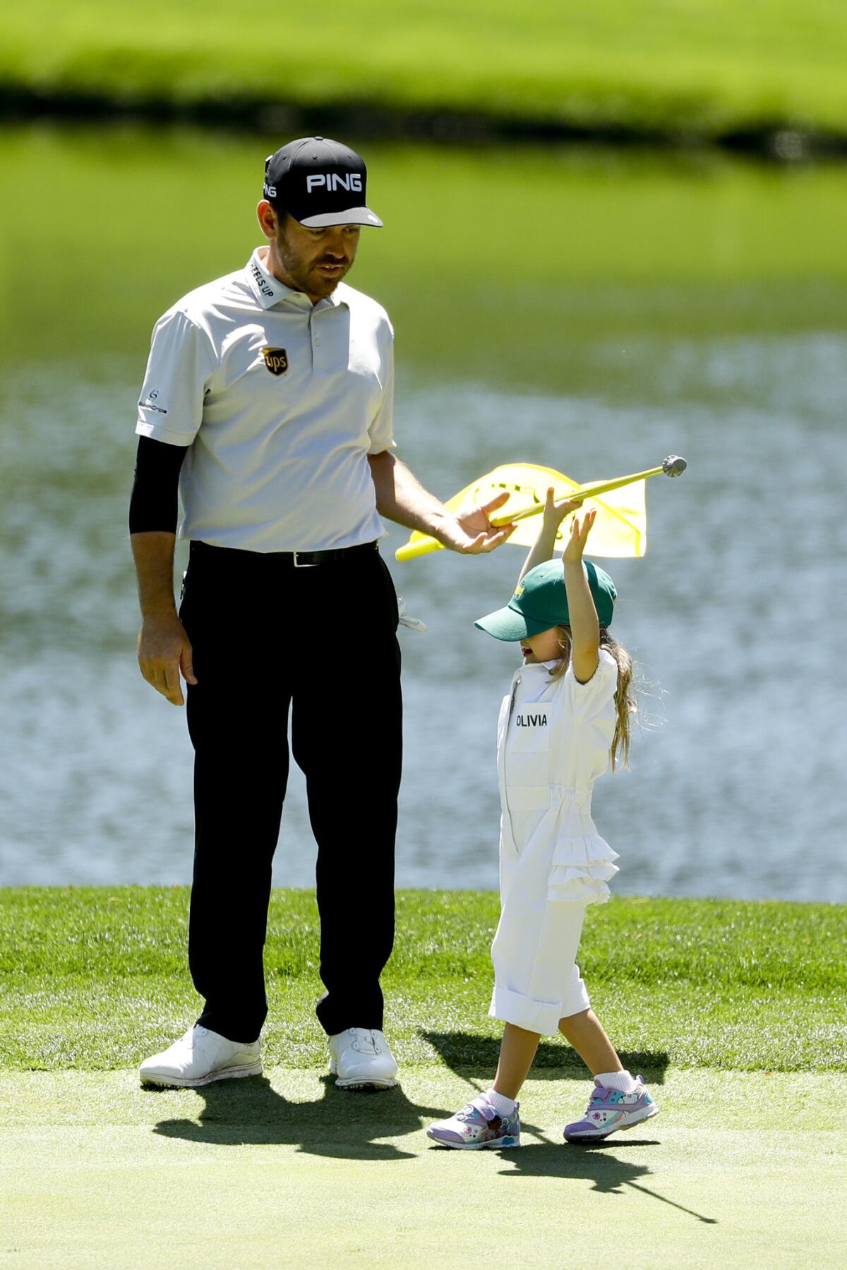Louis Oosthuizen of South Africa helps his daughter Olivia pull the flag on the third hole during the Masters par-three tournament.