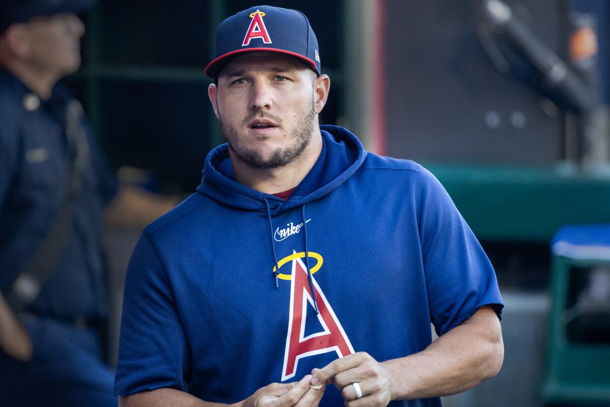 Angels star Mike Trout walks in the team dugout during a game.