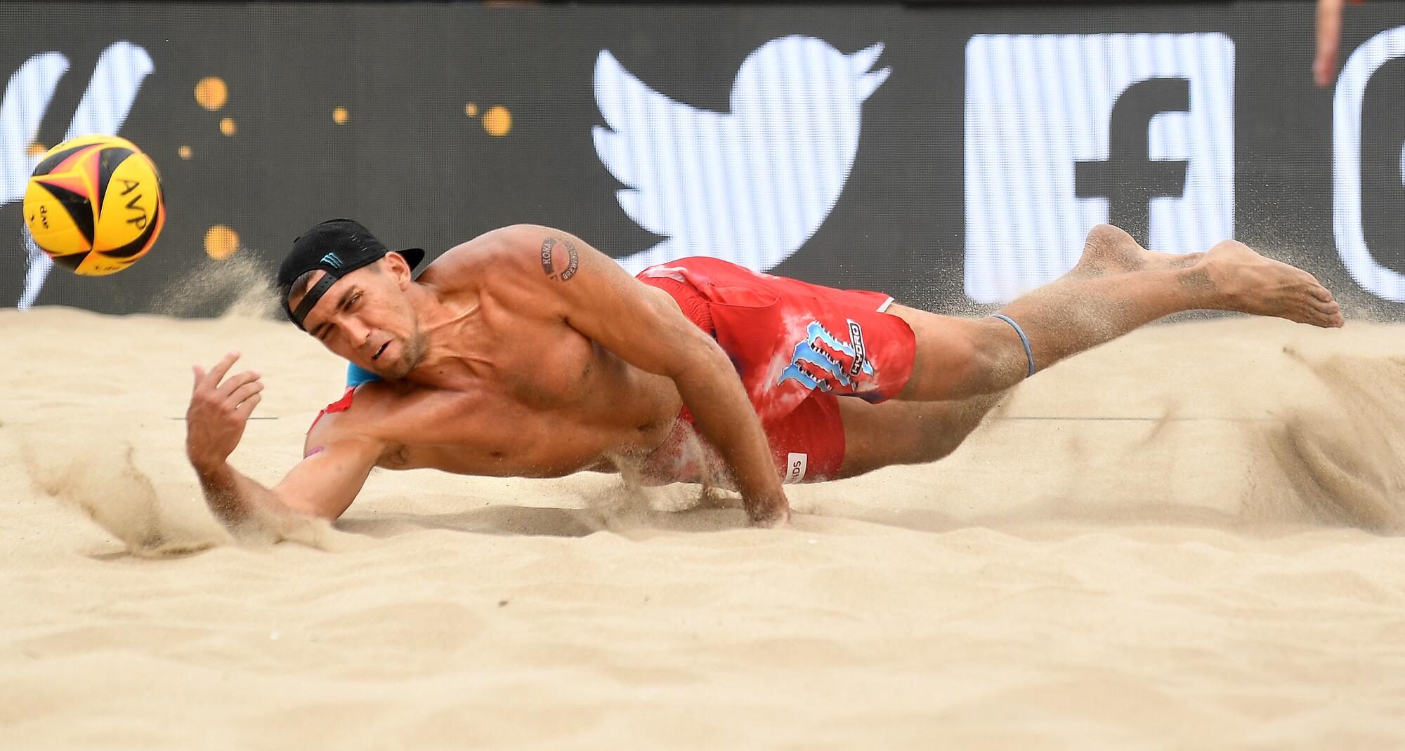 Trevor Crabb dives to the sand in a beach volleyball match.