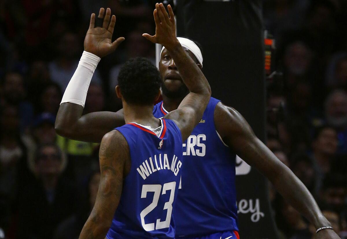 Clippers forward Montrezl Harrell is congratulated by teammate Lou Williams after scoring a basket.