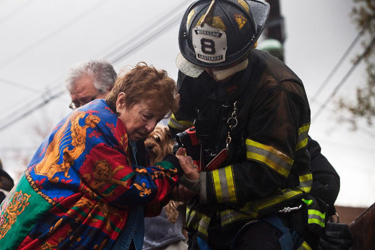 A woman is helped from a truck by a firefighter after being evacuated in New Jersey.