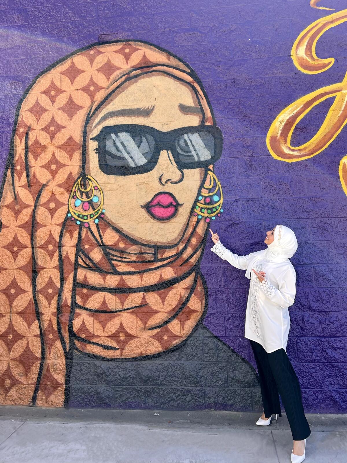 Doaa Zaher poses next to one of the new "Hijabi Queens" murals in Anaheim's Little Arabia District.