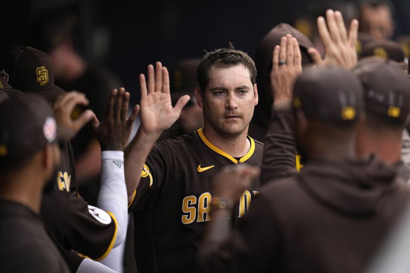 San Diego Padres starting pitcher Seth Lugo, middle, high-fives with teammates after being pulled from the game during the third inning of a spring training baseball game against the Los Angeles Angels, Tuesday, March 7, 2023, in Peoria, Ariz. (AP Photo/Abbie Parr)