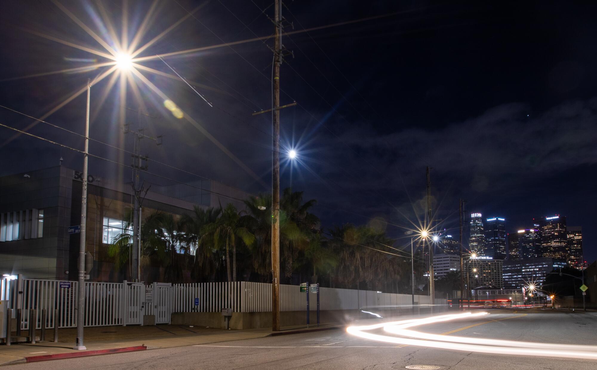 A street in with a curved headlight blur and the L.A. skyline 