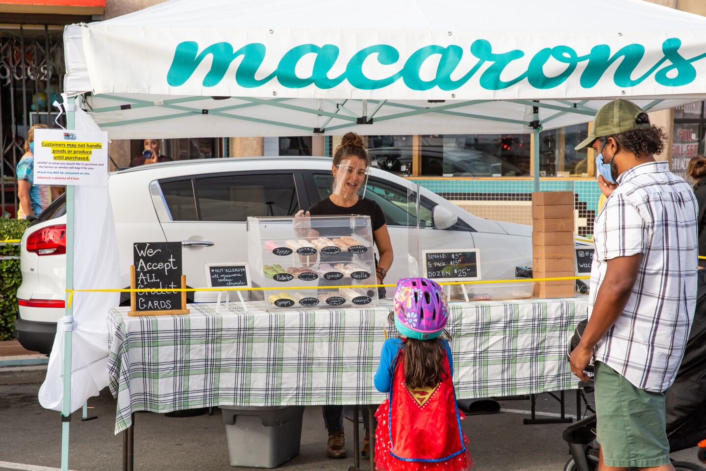 Montague Williams and his daughter check out the macarons at Gigi’s Gluten Free, owned by Lacee Perkins, at the Ocean Beach Farmers Market.