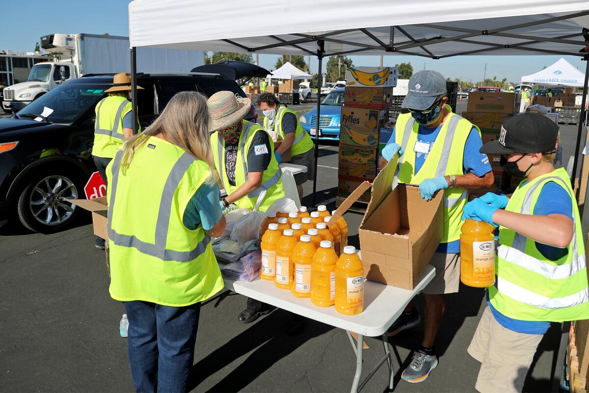Volunteers sort out bottles of orange juice to give out during a drive-through food distribution event at the OC Fairgrounds.