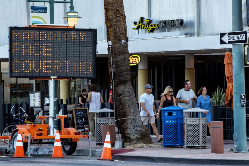 PALM SPRINGS, CA - JULY 16, 2020: Pedestrians ignore the mandatory face coverings order while walking in downtown Palm Springs on July 16, 2020 in Riverside County, California. Riverside County is experiencing a surge in COVID-19 cases.(Gina Ferazzi / Los Angeles Times)