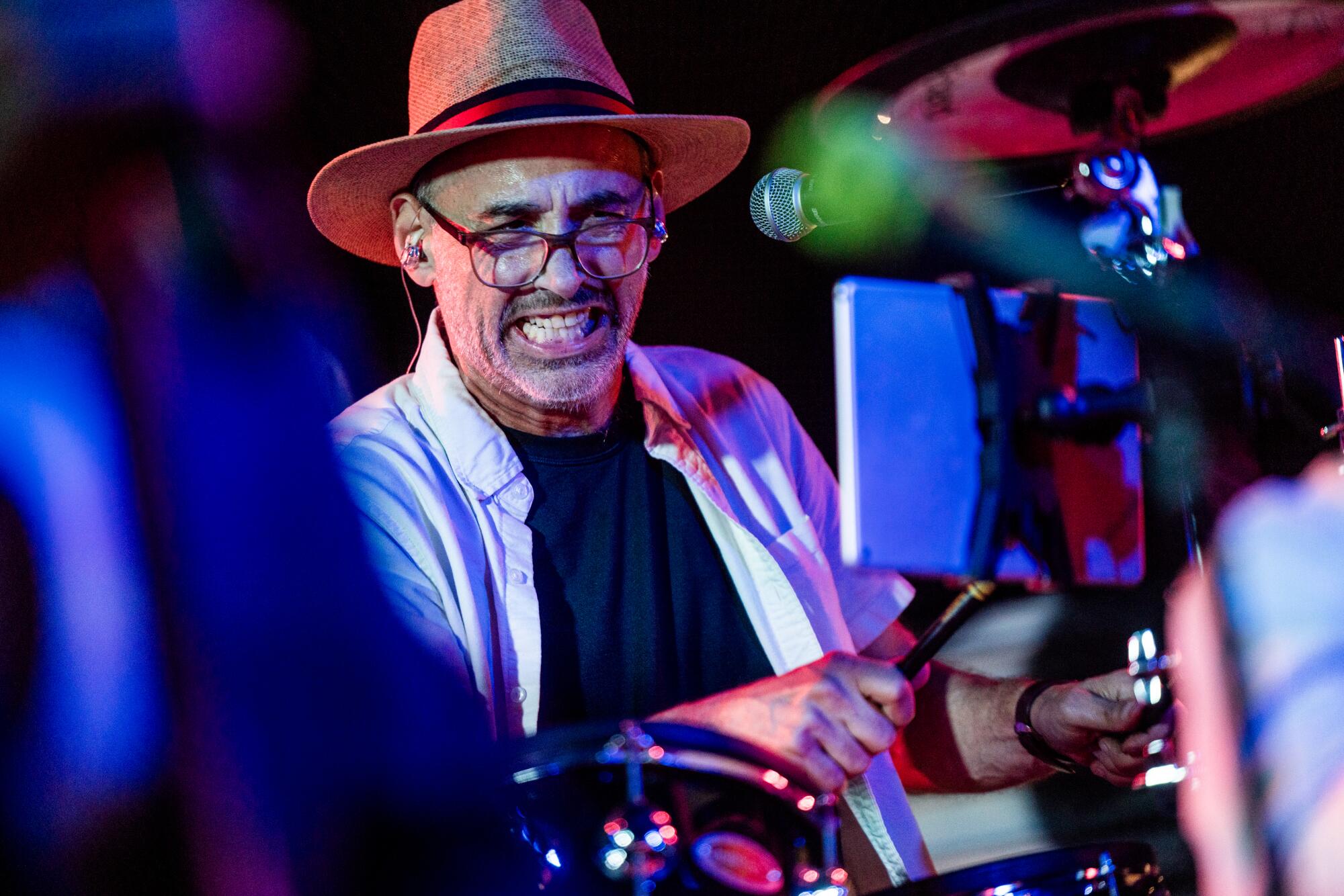 A man wearing a hat plays the drums.
