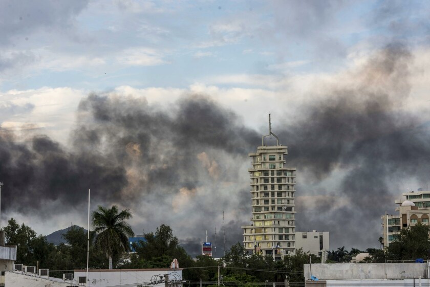 Smoke rises from burning cars amid the gunfight.