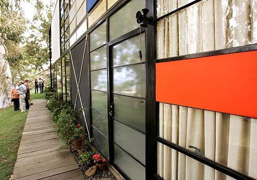 A front view of the Eames Houses glass-and-steel exterior with its X-brace and splash of bright color.