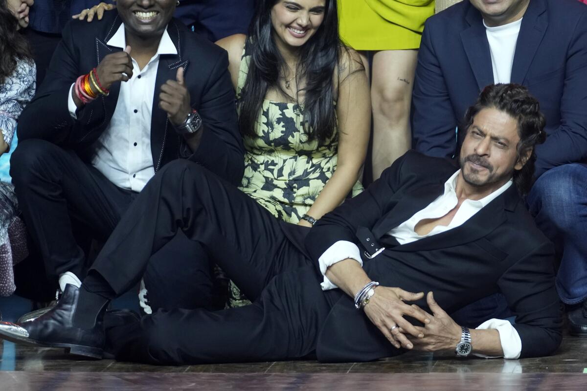 Shah Rukh Khan lies on the floor propped up on an elbow with others behind him.