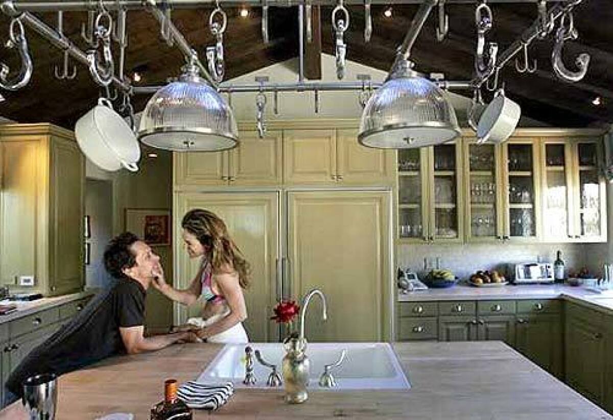 Brian and Gigi Levangie Grazer in their kitchen accented by limestone counters and wood cabinets.