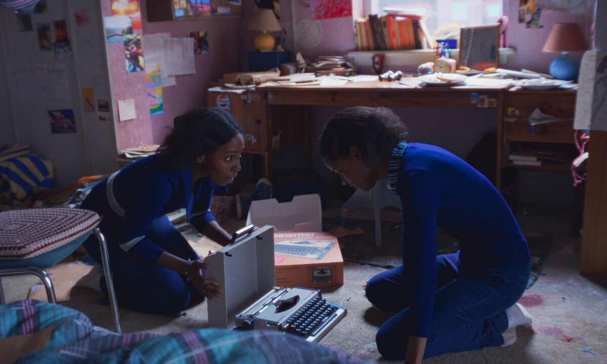 Two young women on their bedroom floor with a portable typewriter at the movie. 