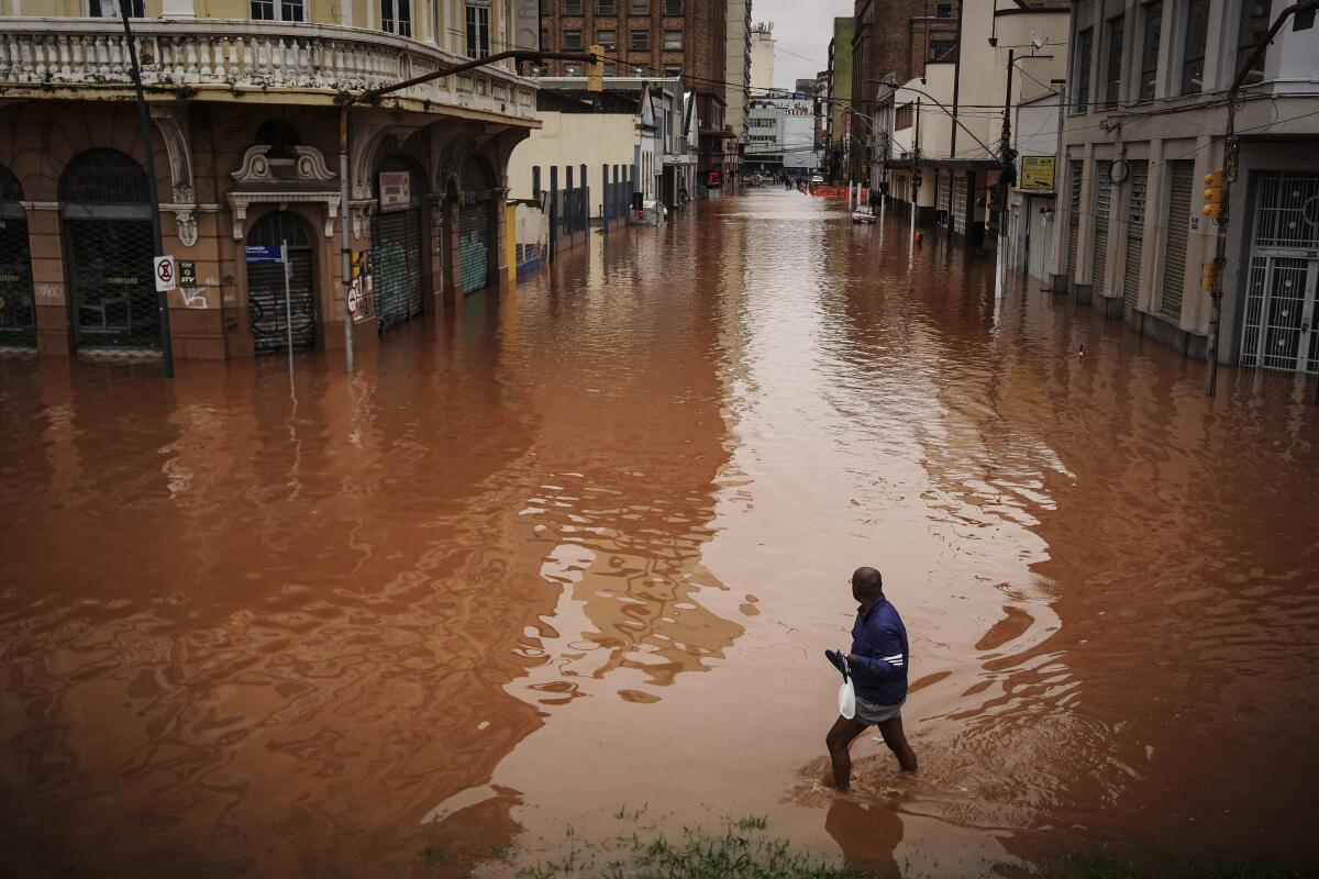 Un hombre camina por una calle inundada debido a las intensas lluvias,