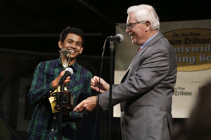 Yash Hande is presented a trophy by Rick Shea, right, President of the San Diego County Board of Education after winning the 48th annual San Diego Union-Tribune Countywide Spelling Bee.
