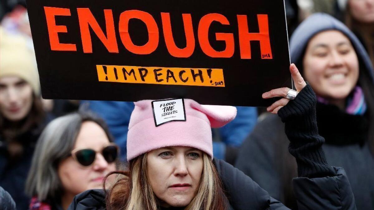 A woman holds a sign expressing support for impeaching President Trump at a rally organized by Women's March NYC in New York on Jan. 19.