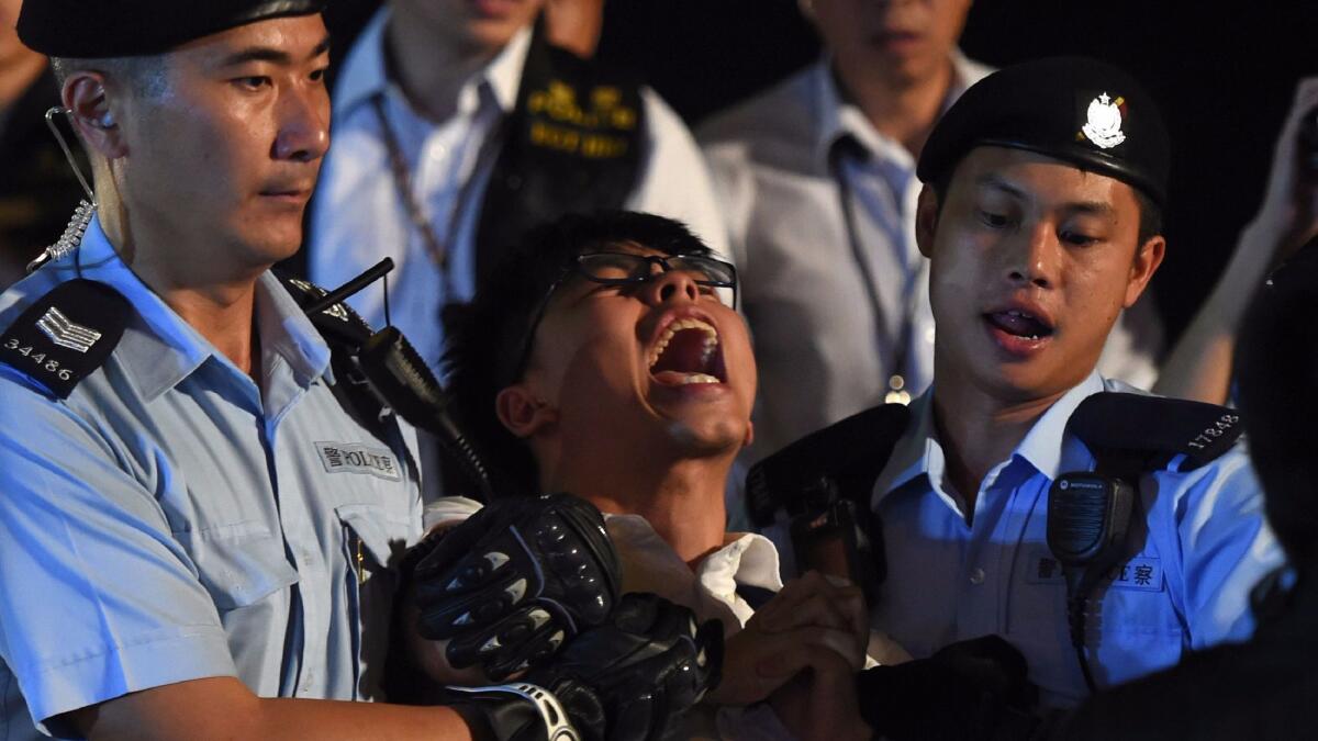 Pro-democracy campaigner Joshua Wong, center, yells as he is taken away by police after he and other demonstrators staged a sit-in protest at the Golden Bauhinia statue in Hong Kong on June 28, 2017.