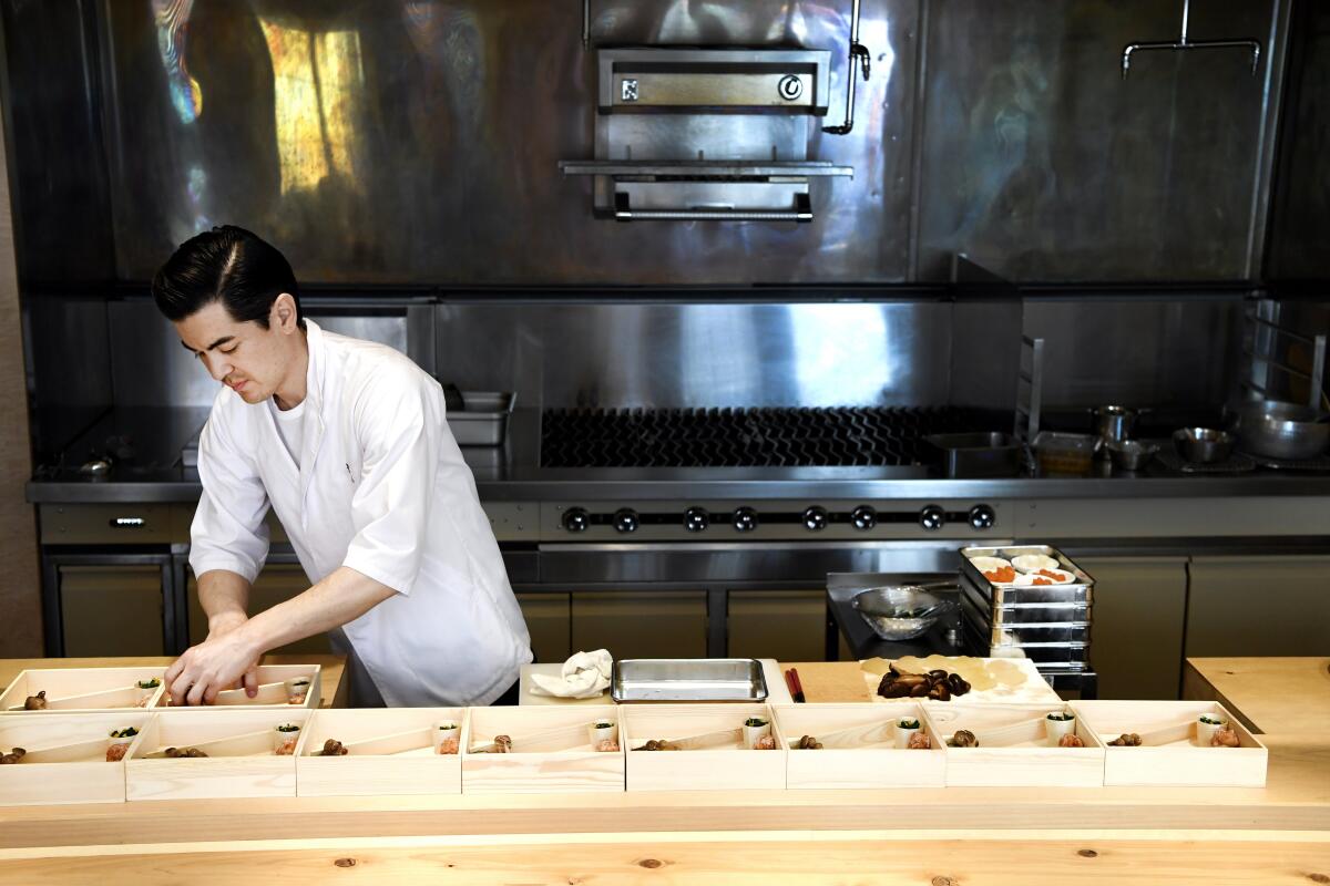 A chef arranges food in bento boxes. 