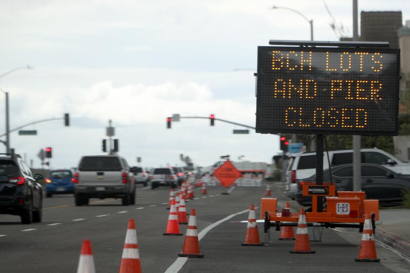 A sign on Pacific Coast Highway reminds drivers that the beach parking lots and pier are closed in Huntington Beach on Friday, April 10, 2020.