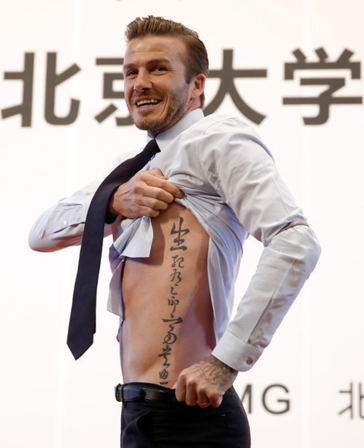 David Beckham shows his tattoo during his visit to Peking University.