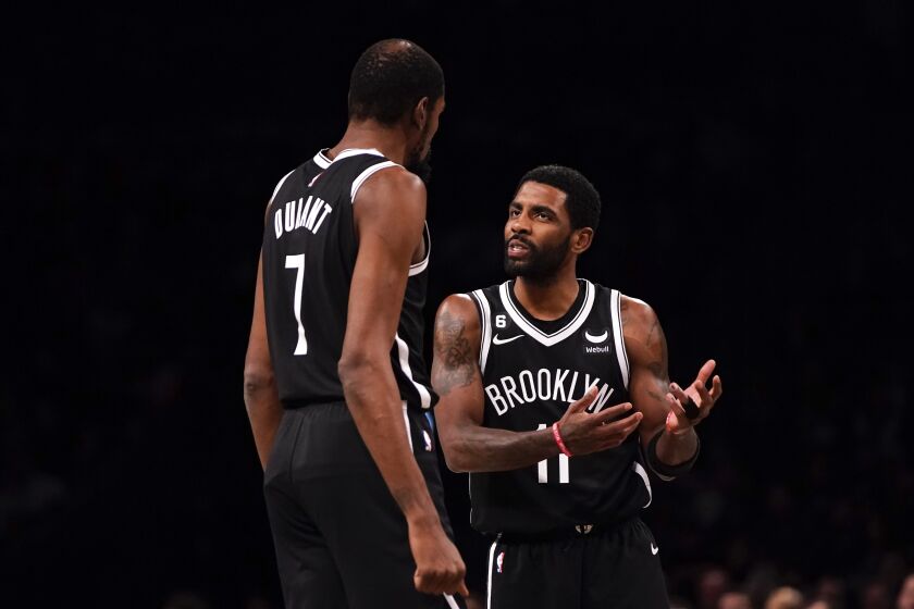 Brooklyn Nets guard Kyrie Irving talks to forward Kevin Durant (7) during the first half of an NBA basketball game against the Orlando Magic, Monday, Nov. 28, 2022, in New York. (AP Photo/Julia Nikhinson)
